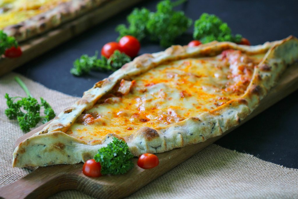 Close-up of a delicious Turkish pide with cheese and tomatoes on a cutting board.