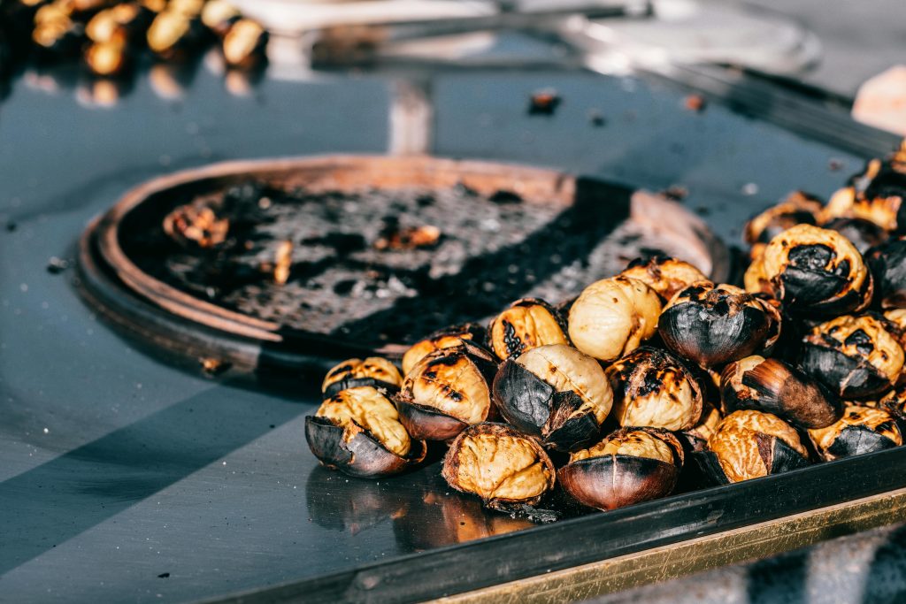 A close-up of freshly roasted chestnuts on a metal pan in a bustling Istanbul street market.